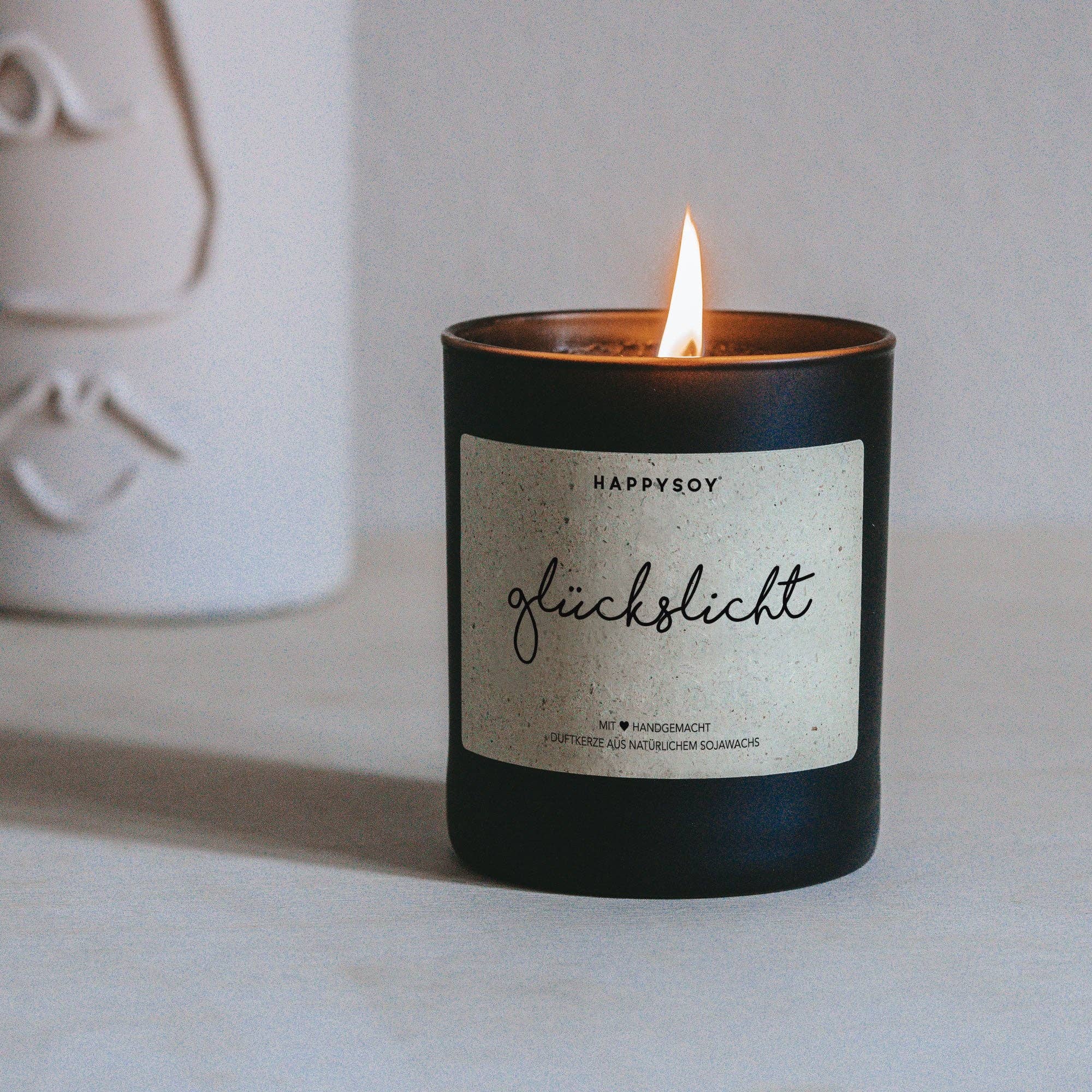Duftkerze aus Sojawachs von Happysoy, Glückslicht von Miaflora, mit sanftem Licht und angenehmem Duft, auf einer eleganten Oberfläche.